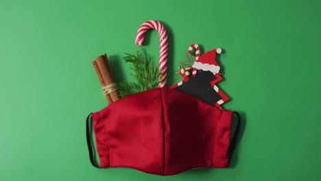 decoraciones de navidad y caña de caramelo con máscara de rostro roja sobre fondo verde