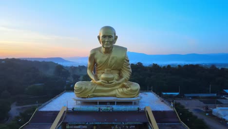 4k-Antenne:-Die-Drohne-Fliegt-In-Der-Abenddämmerung-In-Thailand-Zu-Einer-Riesigen-Mönchsstatue,-Die-Von-Bergen-Aus-Khao-Yai-Umgeben-Ist