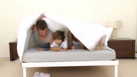 happy family playing under the sheets