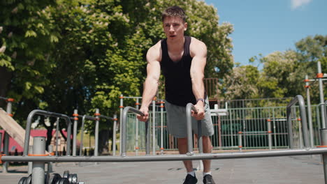 athletic bodybuilder muscular man doing sport workout pushup exercise on parallel bars outdoors