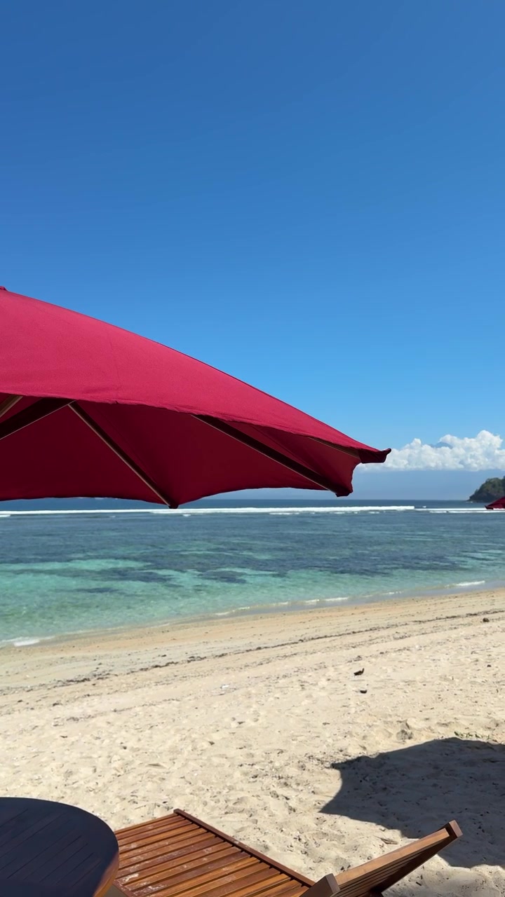 Ombrellone rosso su una spiaggia tropicale con oceano cristallino