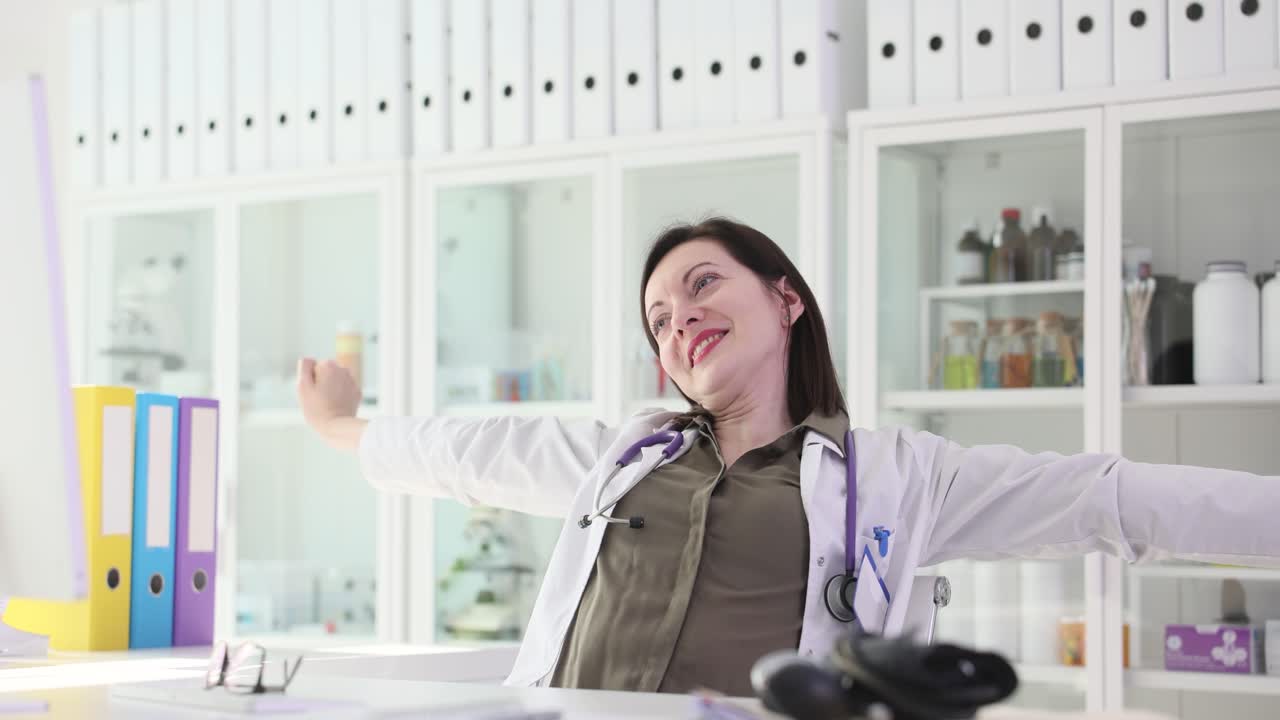 Female doctor stretching and relaxing at her desk in the office