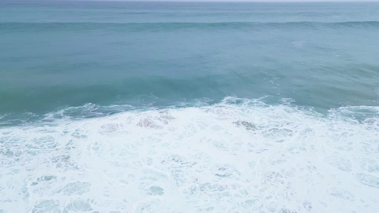 Waves crashing along the serene coastline of Aljizur, Portugal on a calm day
