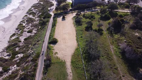 Tilt-up-shot-to-reveal-walkers-using-the-coastal-path-near-Quinns-Beach-with-the-old-caravan-park-redevelopment-site