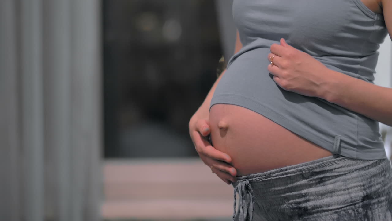 Mujer embarazada acariciando y abrazando su vientre.