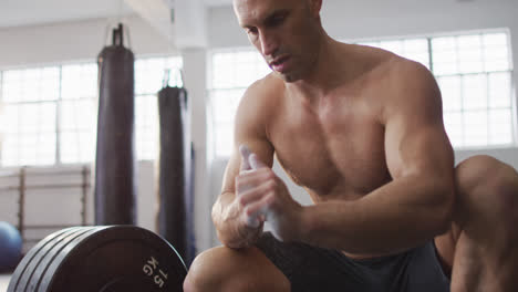 Caucasian-male-trainer-working-out-with-barbell-at-the-gym