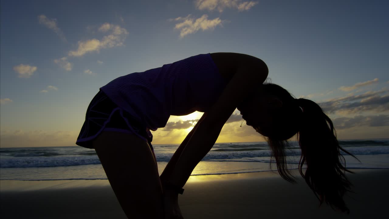 스포츠 시계를 입은 아시아 여성이 해변에서 운동하고 있습니다.