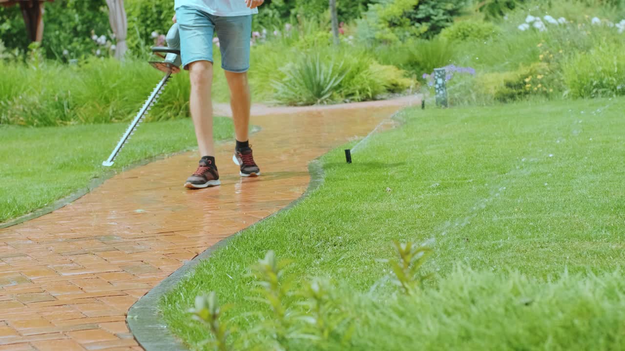 손에 장비를 들고 정원을 걸어다니는 정원사: 시골 생활, 과일 재배, 정원 가꾸기의 개념.