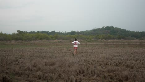 Persona-Corriendo-Por-Un-Campo-Abierto-Con-Vegetación-Y-Colinas-Al-Fondo.