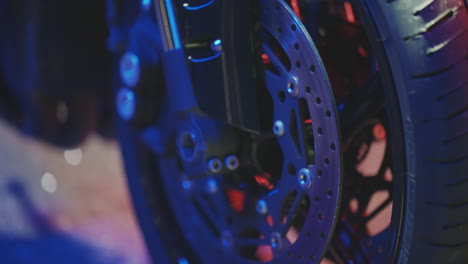 close-up view of a motorcycle wheel and brake disc at night