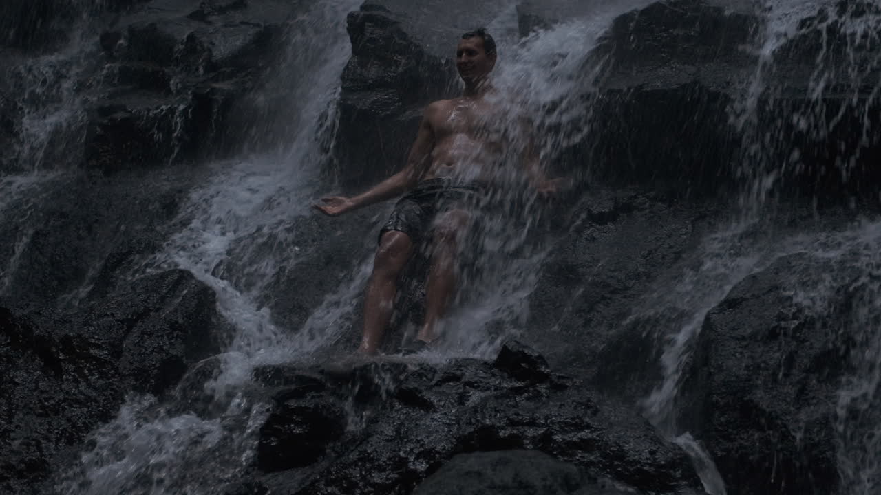 폭포 에 서 있는 젊은 남자.