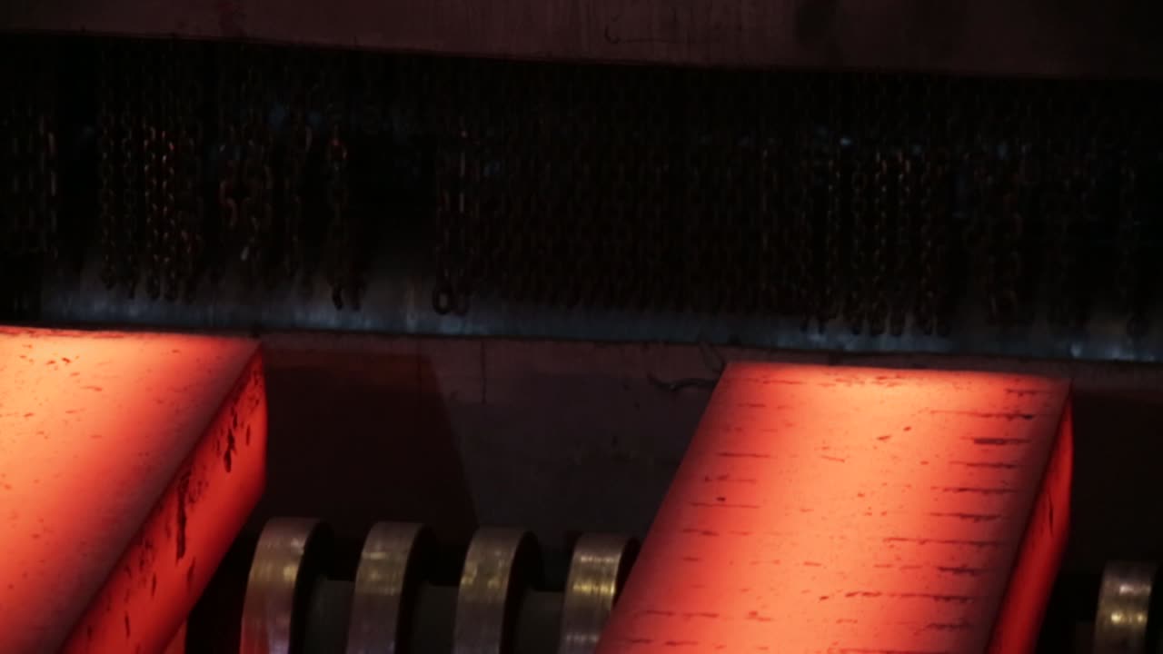 Primo piano di metallo incandescente in un'acciaieria industriale, che evidenzia il calore intenso e i macchinari
