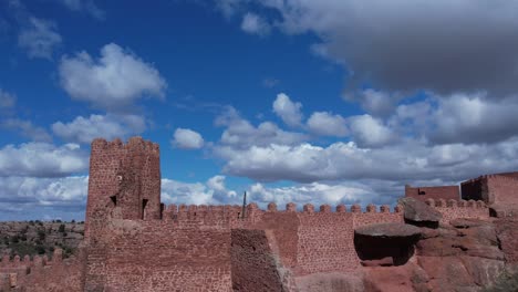 Vista-Aérea-De-Drones-Del-Castillo-De-Peracense,-En-Teruel,-Construido-En-El-Siglo-X-En-La-Cima-De-Una-Colina-Con-Arenisca-Roja-Con-Un-Cielo-Agradable-Cambiante