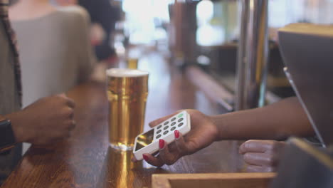 male customer in bar making contactless payment for drinks with smart watch in health pandemic