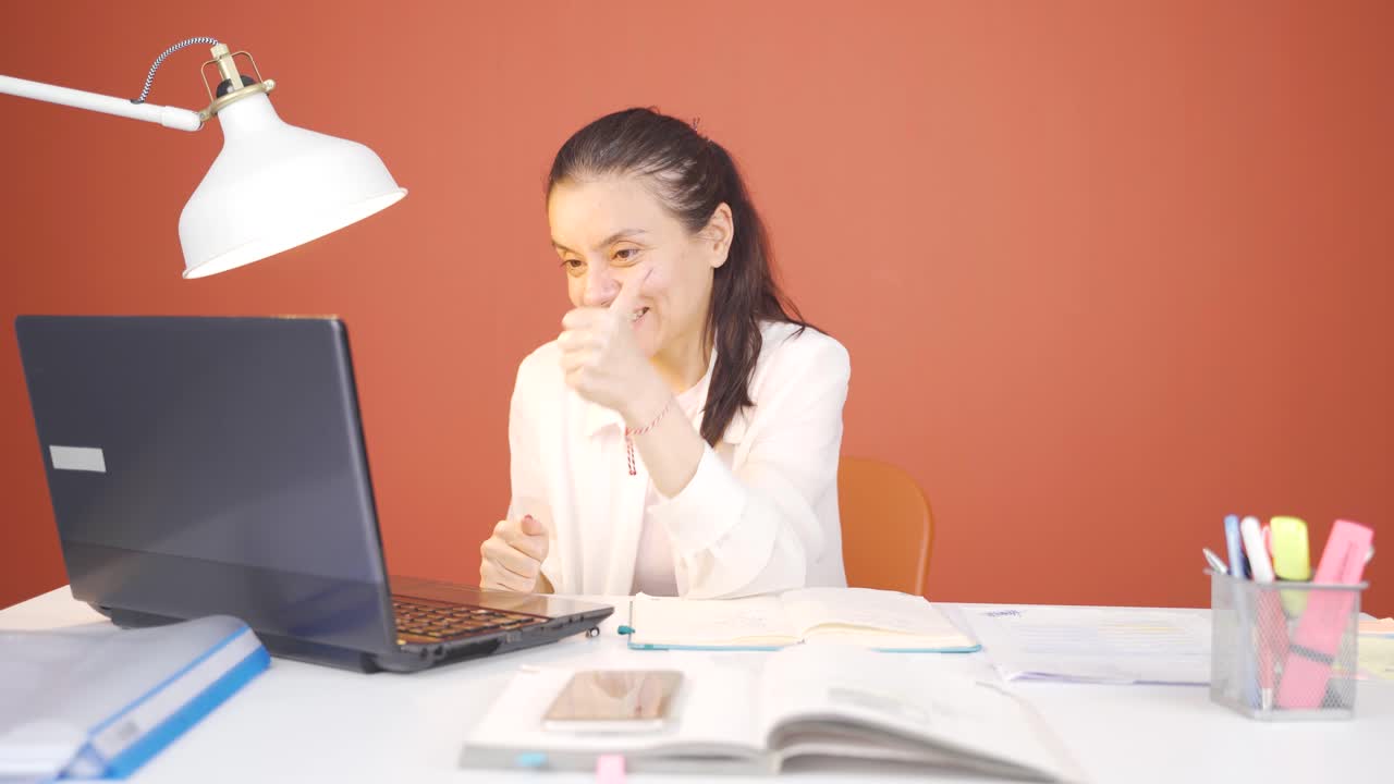 mujer mirando la computadora portátil haciendo un gesto positivo.