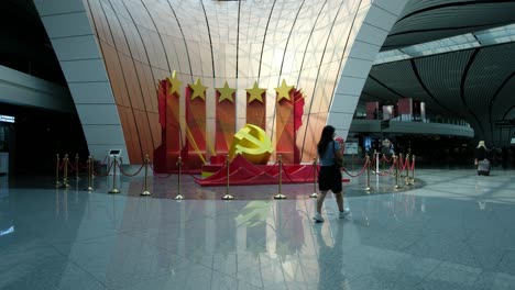 beijing daxing airport central courtyard with travelers passing communist stars and hammer and sickle symbol