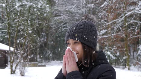 mujer asiática que sopla la nariz durante la nevada en el frío día de invierno