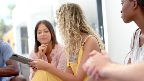 amigos serios diversos y terapeuta femenina con tableta hablando durante la terapia de grupo, cámara lenta