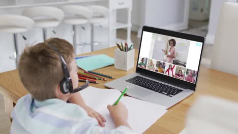 Composite-of-boy-using-laptop-for-online-lesson-at-home,-with-diverse-teacher-and-class-on-screen