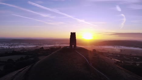 pan aéreo de glastonbury tor al amanecer, con un cielo azul profundo por la mañana