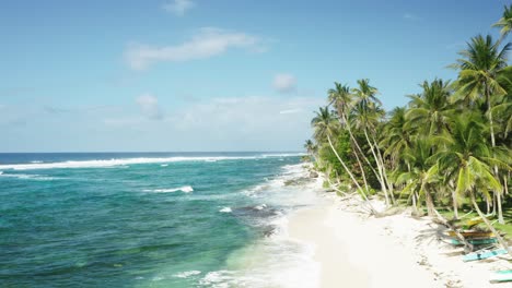 Long-white-sand-beach,-turquoise-water-and-green-palm-trees,-fisherman-boats-on-the-shore