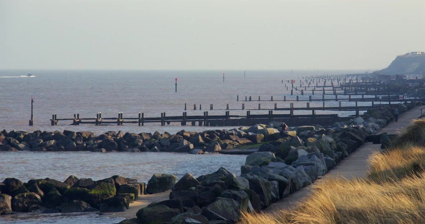 long shot looking south at Hopton holiday village, of the sea and rock Groynes