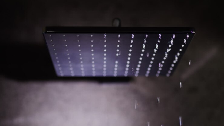 Water flows from a black square nozzle in the shower