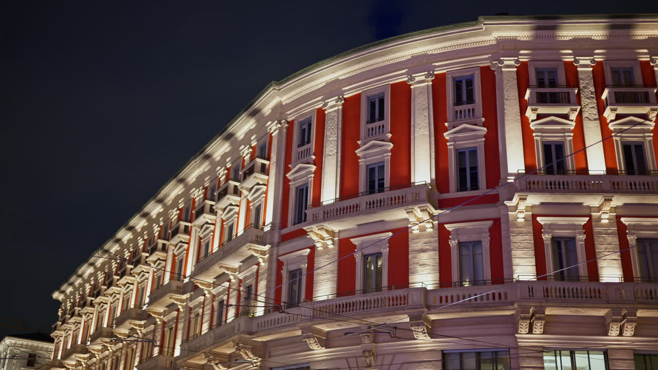 Tall red and white building in the Saint Ambrogio Square in Milan, Italy in the evening