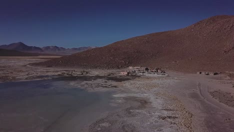 hovering above bolivia's high-altitude plateau, the aerial view unveils a desolate landscape, where the vastness of the terrain is punctuated by a small village settlement