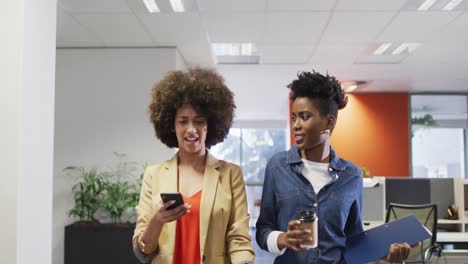 Video-of-happy-diverse-businesswomen-walking-with-smartphone-and-coffee-and-talking