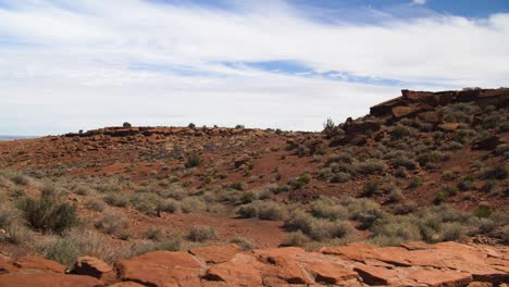 a wide shot of the arid, desert landscape with a stone wall in the foreground at wupatki national monument in arizona
