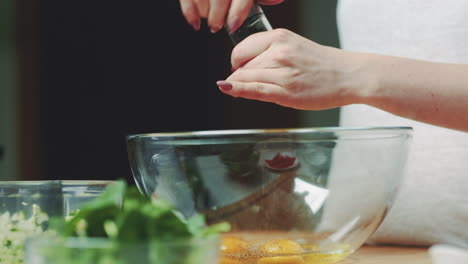 woman seasoning and mixing eggs