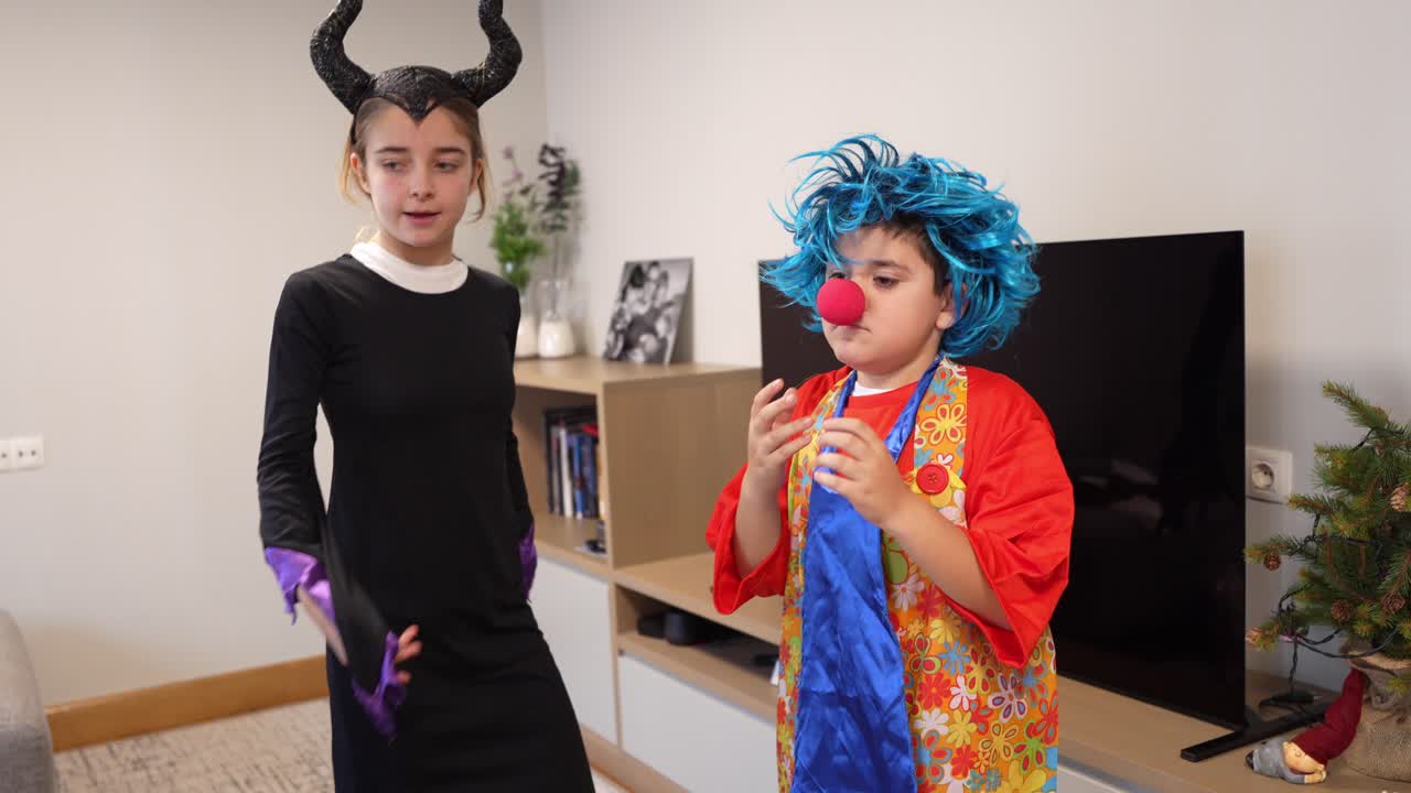 Due bambini vestiti con costumi da strega e clown che giocano in casa