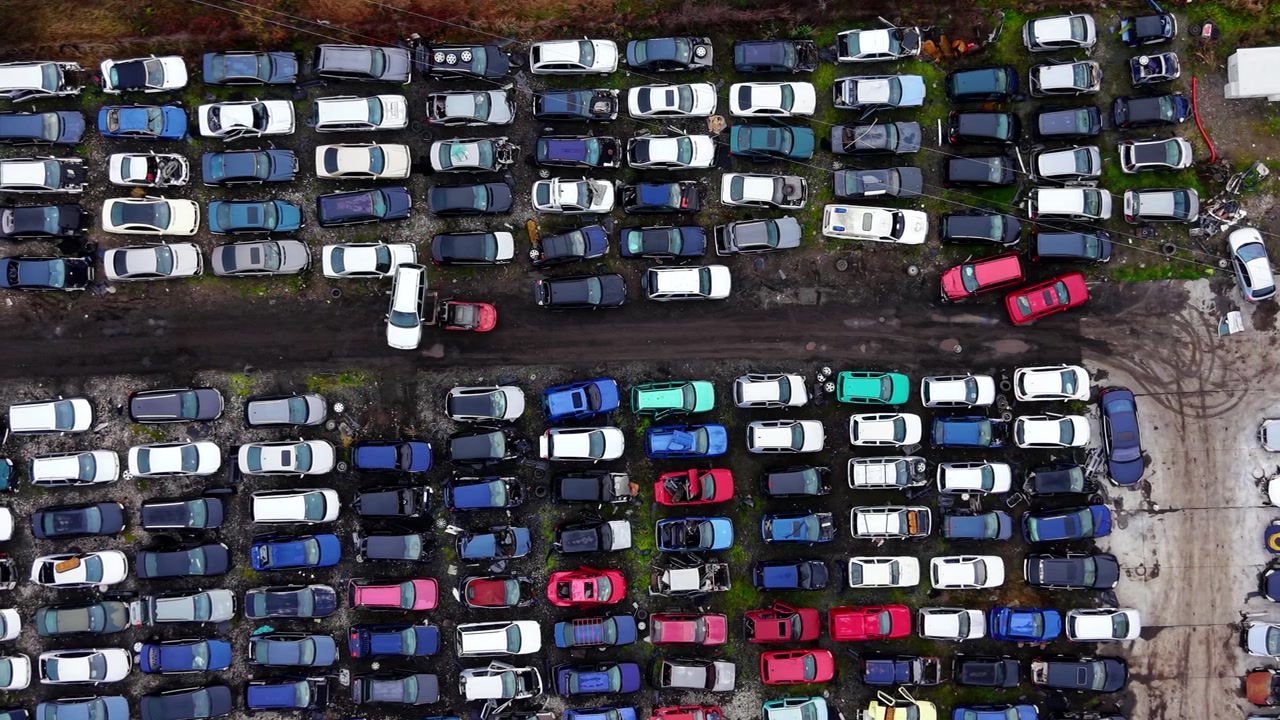Droneperspektiv af adskilte biler. Bredt luftfoto af rækker af strippet køretøjer med spredte hjul ved siden af en asfalteret adgangsvej