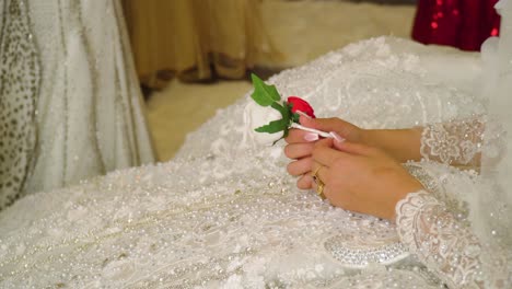 close up on bride hands holding white rose waiting for the groom to celebrate and place this flower on his suit cinematic wedding olive skin roma gypsy red dress walking in the background