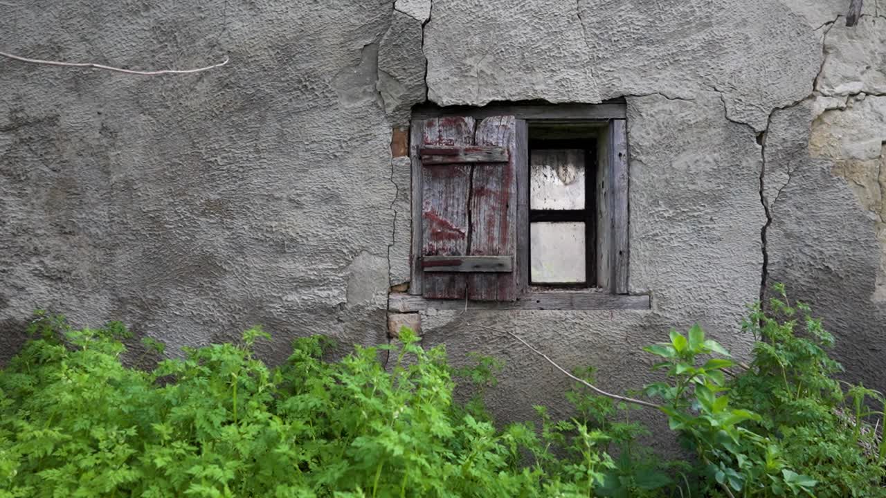 Cracked exterior wall with rustic wooden shutters and aged window