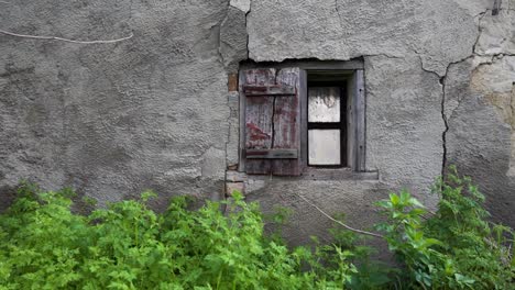 cracked exterior wall with rustic wooden shutters and aged window