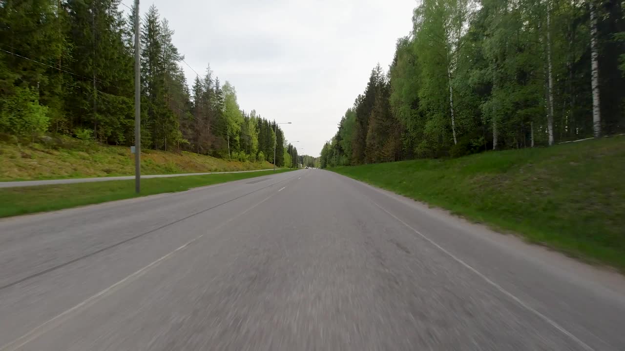 Guidando velocemente lungo una splendida strada finlandese con una foresta verde su entrambi i lati.