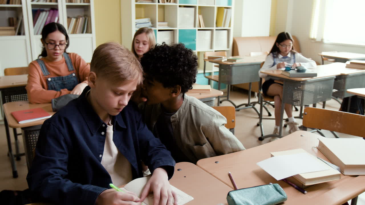 Students whispering in a classroom during a lesson