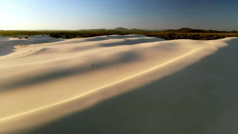 wide drone shot of dark point sand dunes with man on sand dunes in the distance at hawks nest, new south wales, australia