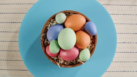 feliz fiesta de pascua. huevos de colores en un cuenco sobre fondo azul vista superior giratoria. preparándose para la pascua, pintando y decorando huevos. celebración cristiana, tradiciones familiares.