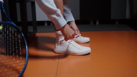 tennis player tying shoes in locker room