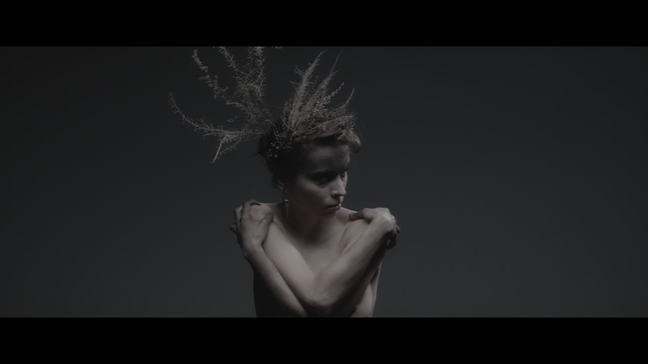Uma mulher vestida como mãe natureza move-se lentamente em um movimento de dança
