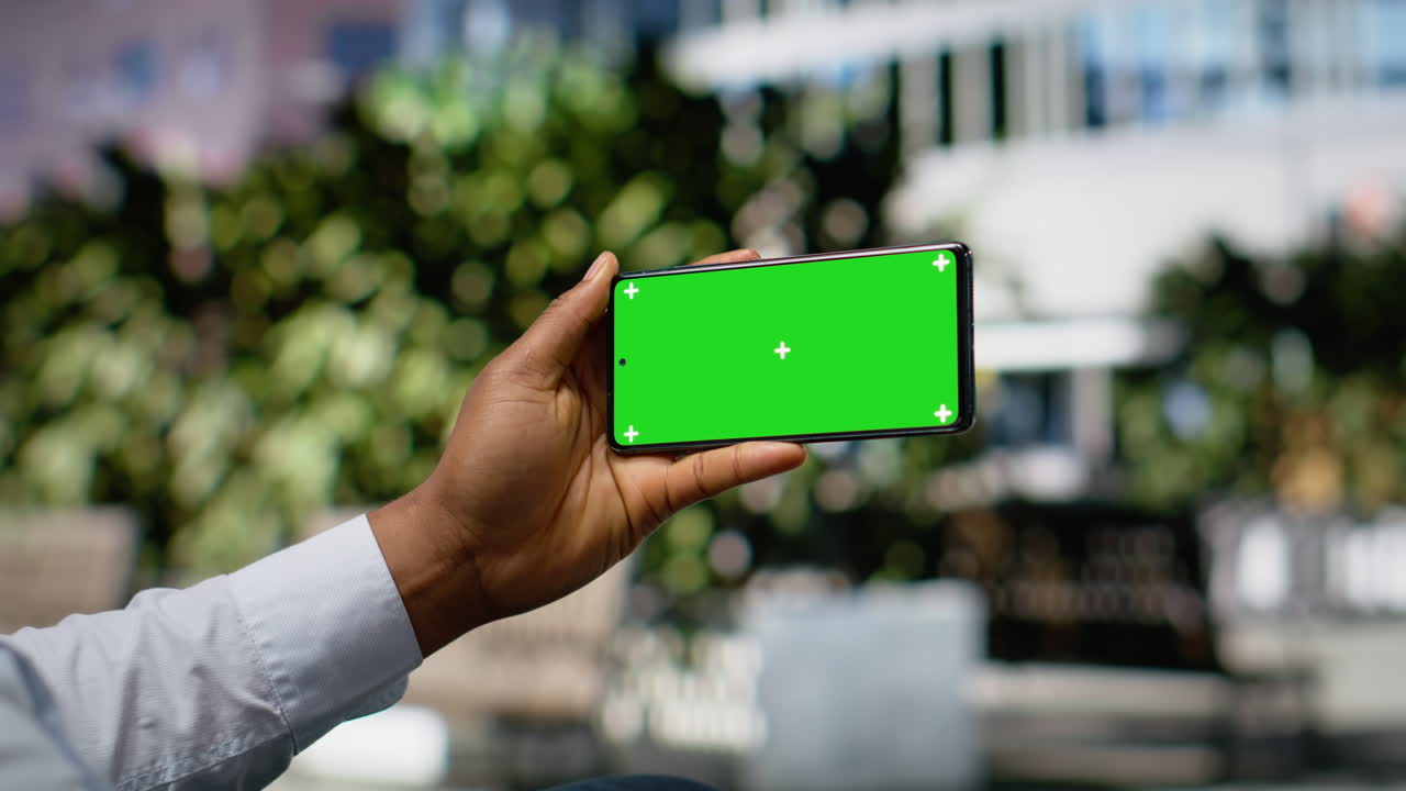 Horizontal chroma key on phone with black man sitting on a park bench