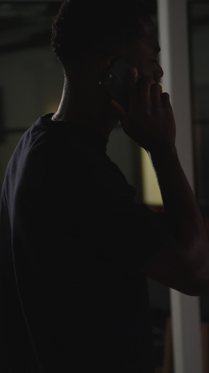 Vertical Video Of Young Man At Home Talking On Mobile Phone At Night Looking Frustrated And Angry 1