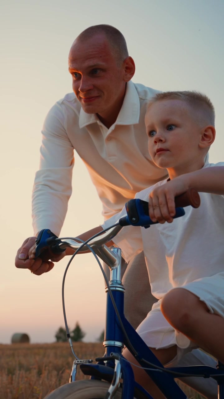 Padre che insegna al figlio piccolo ad andare in bicicletta al tramonto