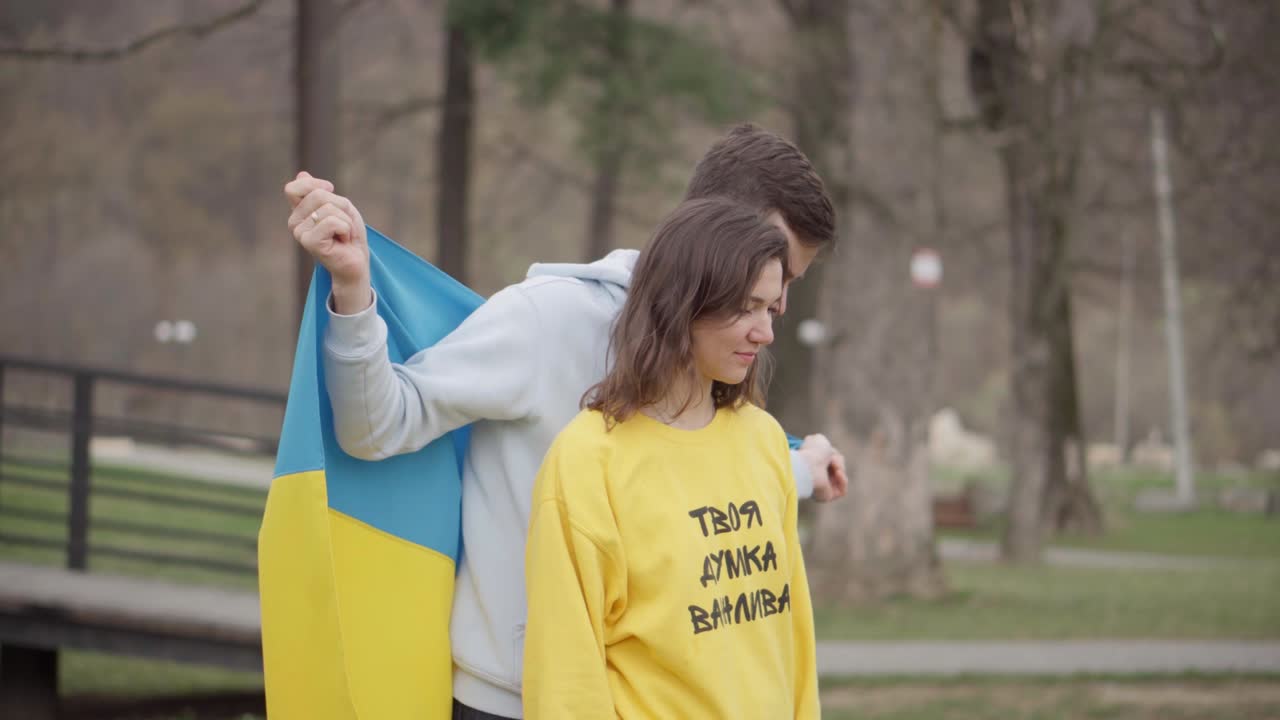 소녀와 소년은 우크라이나 발을 들고 걸어가고 있습니다. 공감의 상징입니다. 소녀의 스웨터에 새겨진 글자: "당신의 의견은 중요합니다."