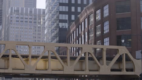 Chicago-metro-train-gliding-through-the-city-on-a-sunny-day,-framed-by-towering-buildings