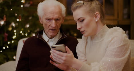 woman teaching grandfather to use cellphone in christmas 1