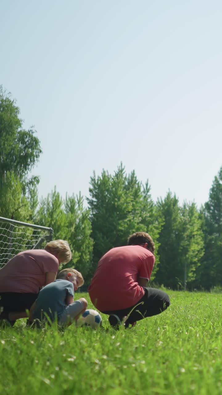 은 날에 신발를 는 가족의 뒷면, 근처에 작은 골포스트와 배경에 흐릿한 더 큰 골포스트
